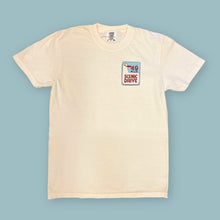 Load image into Gallery viewer, An off-white short-sleeve crewneck t-shirt with a small graphic printed on the left chest, displayed flat against a solid light blue background.